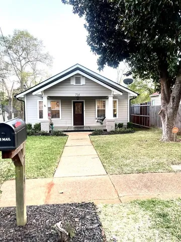 a front view of a house with a yard and trees