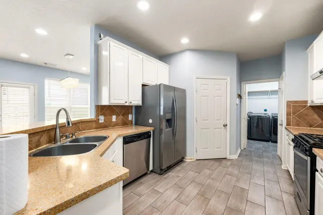 a kitchen with stainless steel appliances granite countertop a refrigerator and a sink