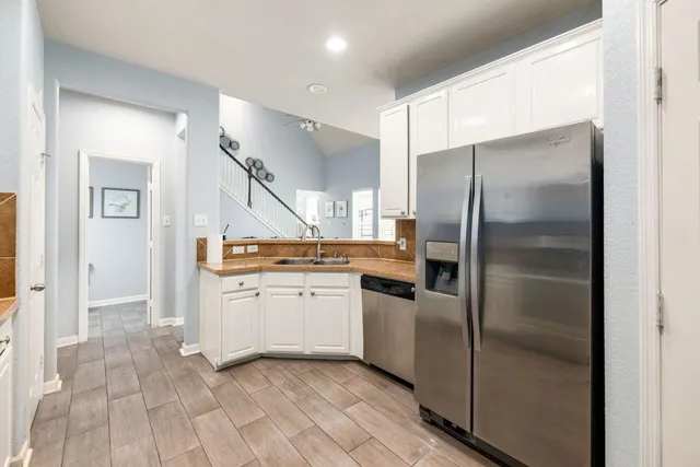 a kitchen with a sink a refrigerator and a stove top oven with wooden floor