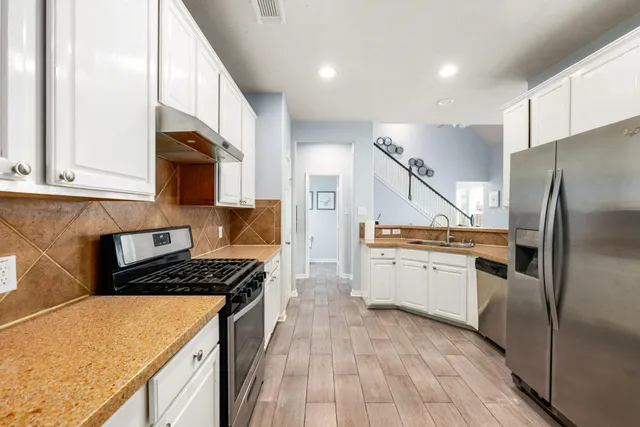 a kitchen with granite countertop white cabinets and stainless steel appliances