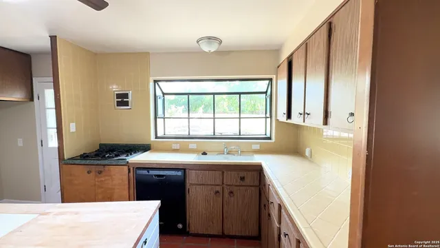 a kitchen with a sink a stove cabinets and a window