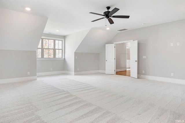 an empty room with ceiling fan and windows