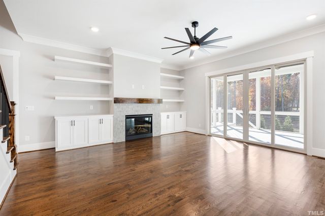 a view of a livingroom with wooden floor a ceiling fan and windows