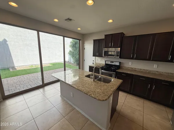 a kitchen with kitchen island granite countertop a sink counter top space appliances and cabinets