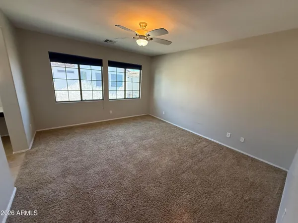 an empty room with windows and a ceiling fan
