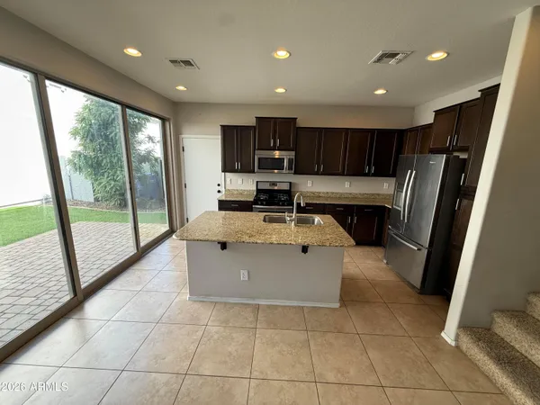 a kitchen with stainless steel appliances granite countertop a refrigerator a sink a stove top oven and a large window