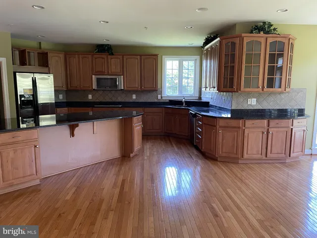a kitchen with granite countertop wooden floors and wooden cabinets