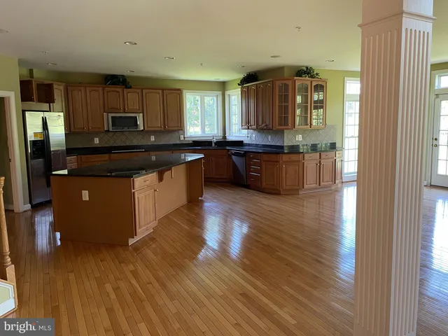 a kitchen with stainless steel appliances granite countertop a stove and a wooden floors