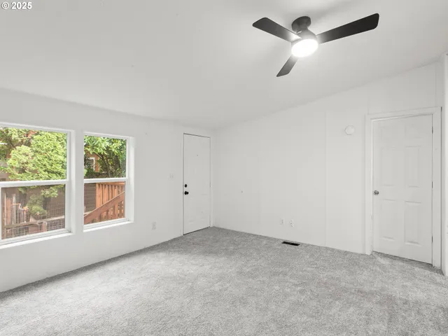 an empty room with a window and a fan