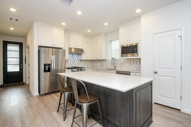 a kitchen with a sink a refrigerator a counter top space and cabinets