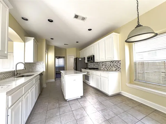 a kitchen with granite countertop a refrigerator stove and microwave