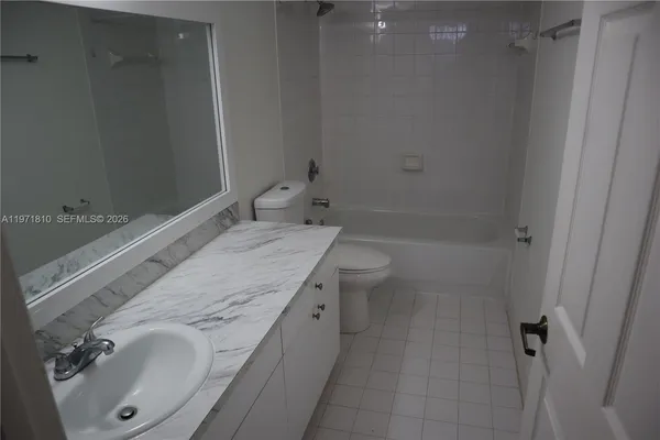 a bathroom with a granite countertop sink a toilet and shower