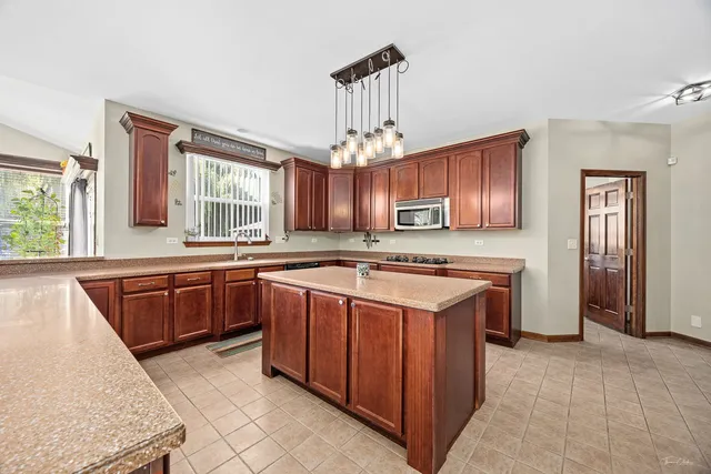 a kitchen with stainless steel appliances granite countertop a sink dishwasher and a refrigerator with wooden floor