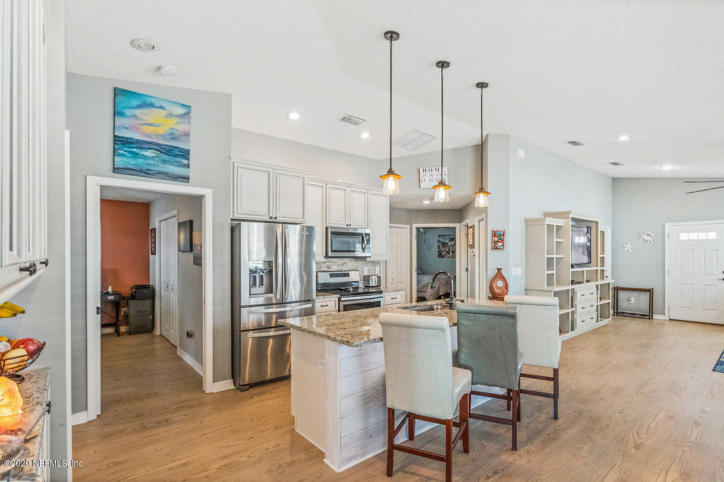 405 2nd Street St. Augustine, FL 32084 - Photo 31 of 49 a kitchen with stainless steel appliances kitchen island granite countertop a refrigerator a oven a sink a dining table and chairs with wooden floor