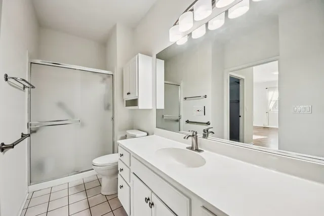 a bathroom with a sink a toilet a mirror and shower