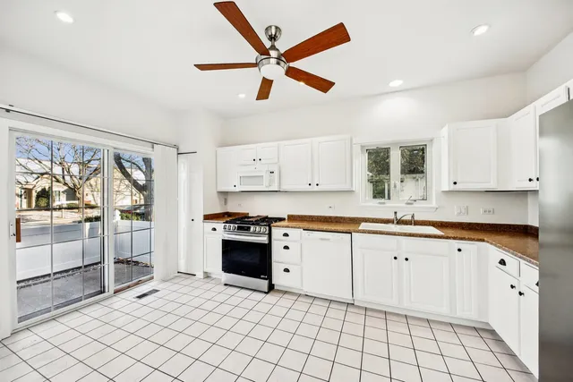a large kitchen with white cabinets a stove a sink and a counter top space