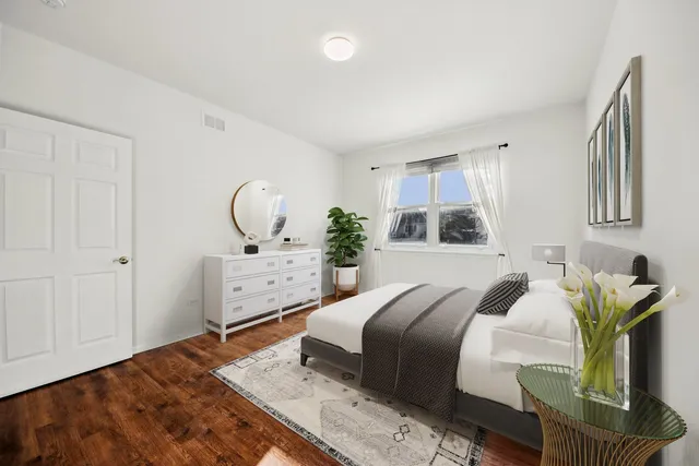 a bedroom with a bed a mirror and a potted plant