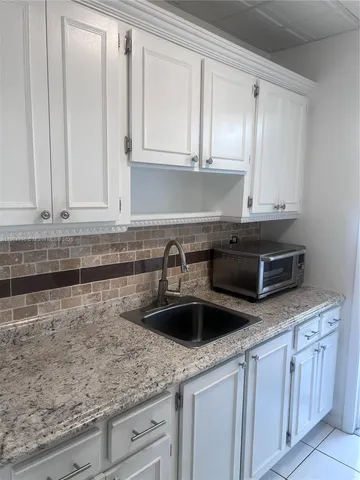 a kitchen with granite countertop white cabinets and a sink