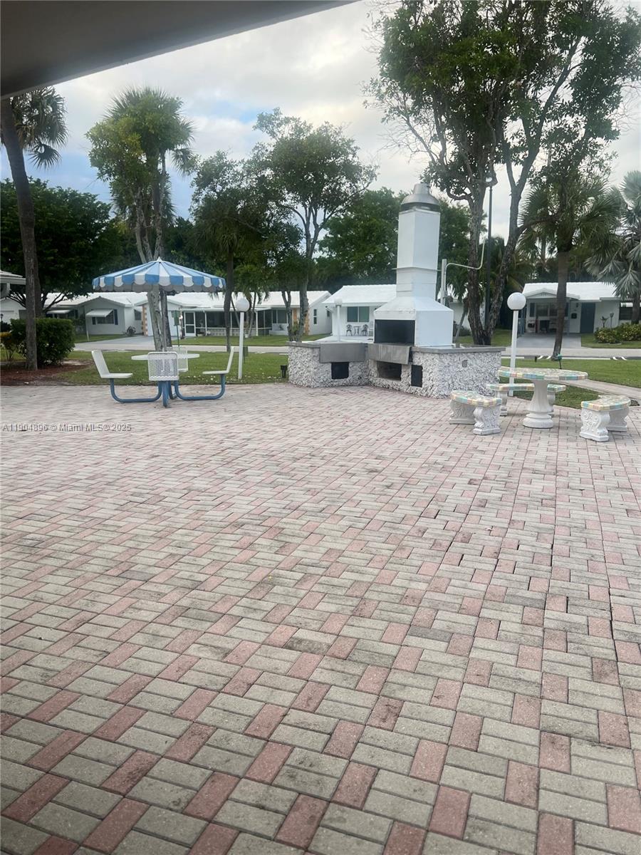 2501 West Golf Boulevard, Unit 128 Pompano Beach, FL 33064 - Photo 37 of 51 a view of a yard with plants and a barbeque