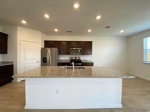 213 Saide Street Georgetown, TX 78626 - Photo 8 of 32 Spacious kitchen featuring a large central island with a light-toned countertop, dark wood-finish cabinetry, stainless steel appliances, and recessed lighting