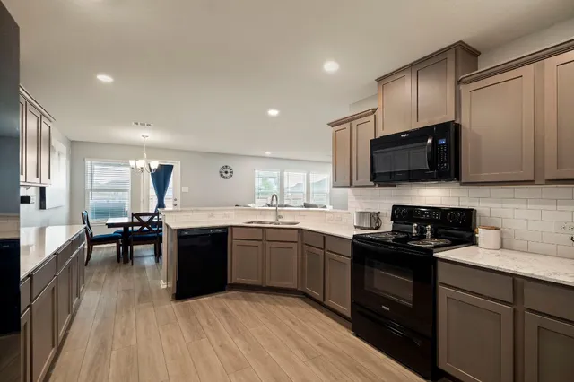 a kitchen with stainless steel appliances granite countertop wooden cabinets a stove top oven a sink and dishwasher