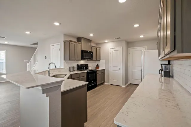 a kitchen with stainless steel appliances kitchen island sink refrigerator and cabinets