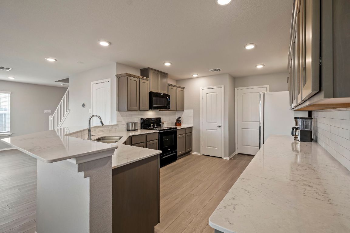 19417 James Carter Jr Street Manor, TX 78653 - Photo 9 of 37 a kitchen with stainless steel appliances kitchen island sink refrigerator and cabinets