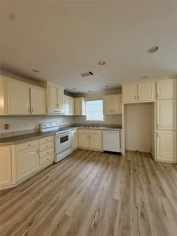 a large kitchen with a wooden floor and stainless steel appliances