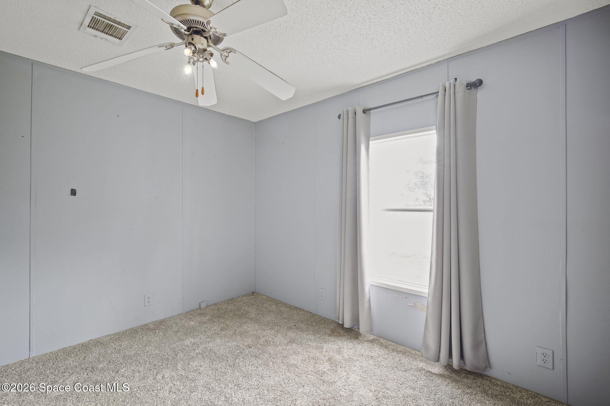 3918 East Ridgewood Drive Cocoa, FL 32926 - Photo 18 of 27 an empty room with a chandelier fan and windows