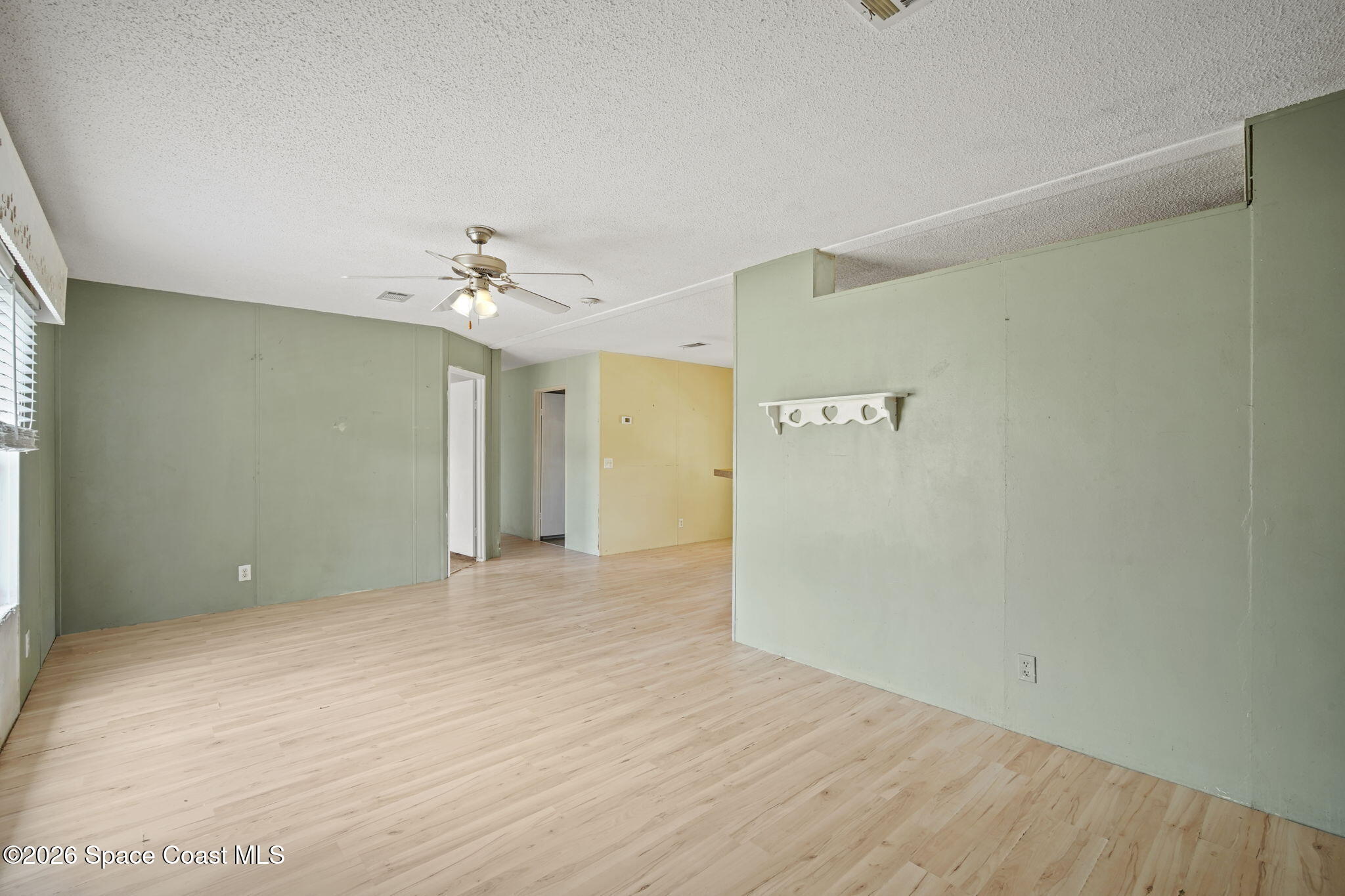 3918 East Ridgewood Drive Cocoa, FL 32926 - Photo 6 of 27 a view of a big room with wooden floor and a chandelier fan