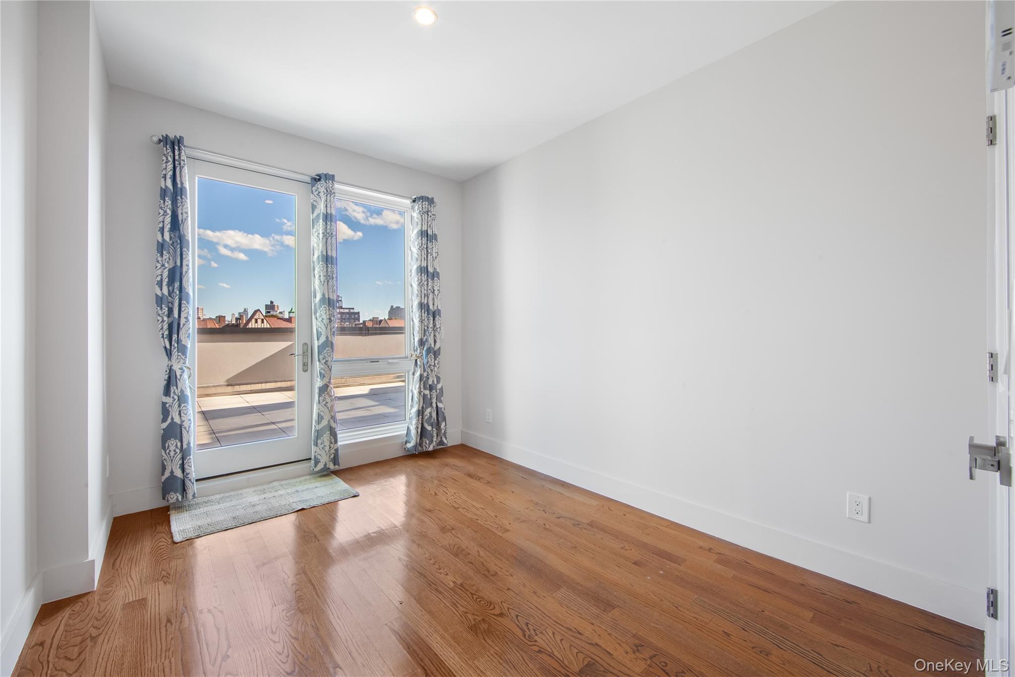 109-19 72nd Road, Unit 7B Queens, NY 11375 - Photo 12 of 17 an empty room with wooden floor door and windows