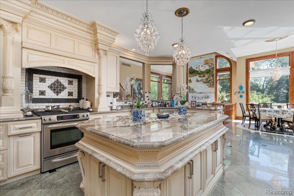3543 Cedar Brook Drive Rochester, MI 48309 - Photo 16 of 99 Gourmet kitchen featuring a large central island with a polished countertop, custom cabinetry with ornate detailing, stainless steel range, decorative tile backsplash, and polished floor tiles