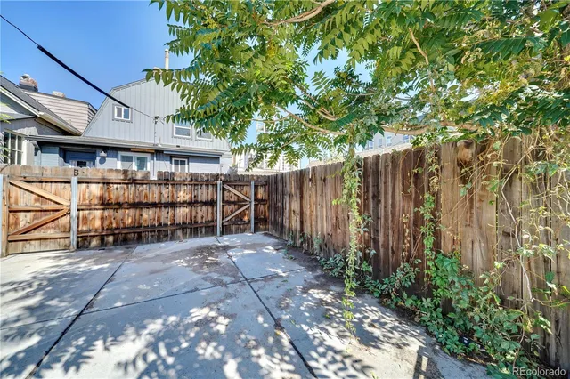 a view of a backyard with wooden fence and a large tree