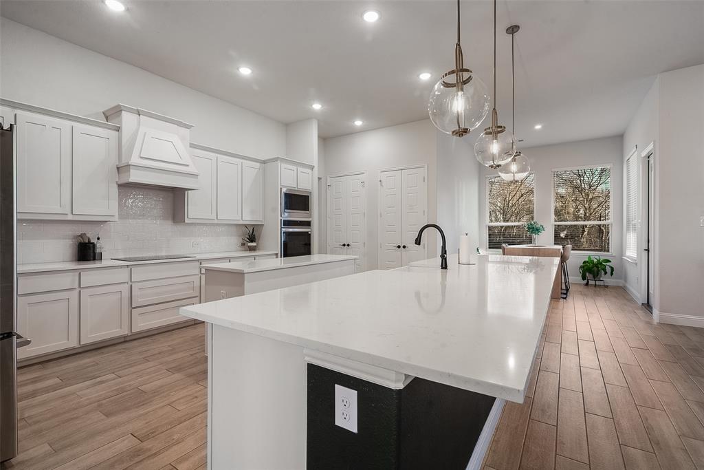 1843 Granite Way Van Alstyne, TX 75495 - Photo 18 of 39 a large kitchen with kitchen island a stove a sink a refrigerator and white cabinets with wooden floor
