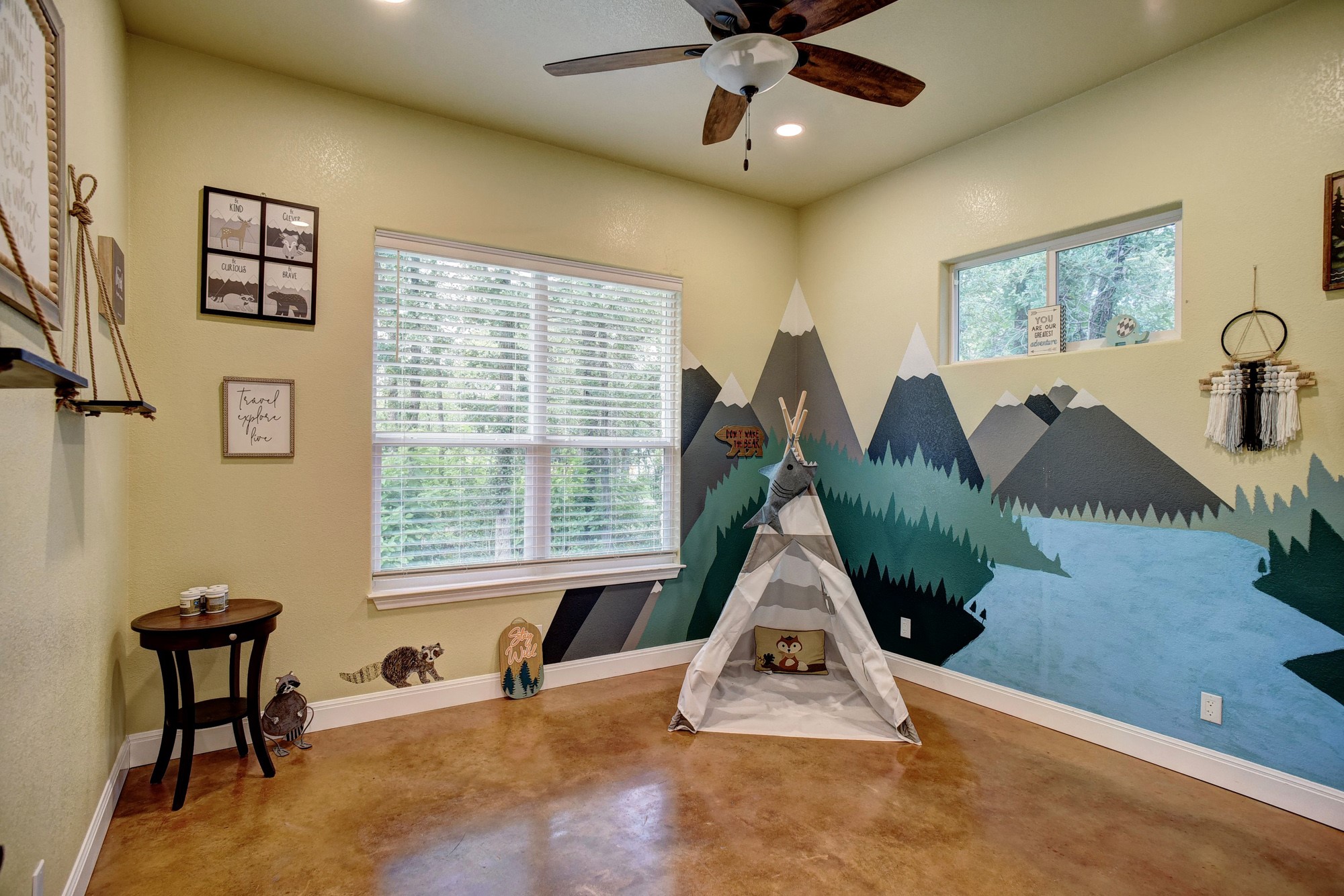 115 Pine Point Cove Elgin, TX 78621 - Photo 21 of 39 A vibrant room with nature-inspired wall murals, featuring ample light from multiple windows and durable concrete flooring.