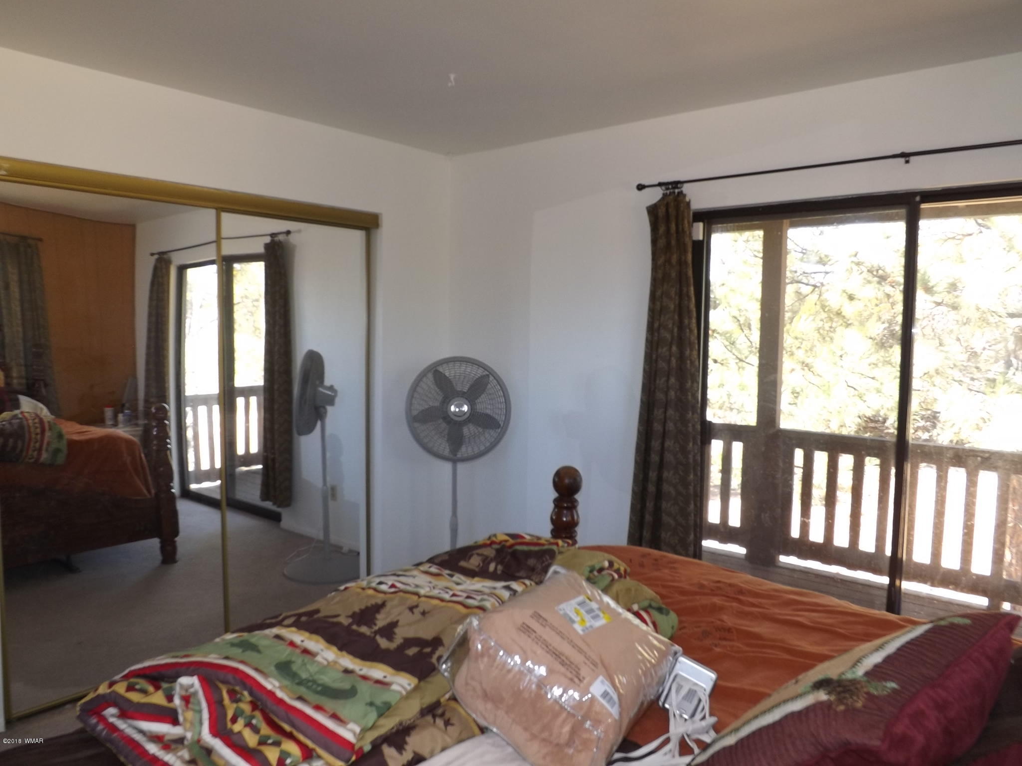 2850 Lodgepole Road Overgaard, AZ 85933 - Photo 32 of 33 a bedroom with a bed a mirror and a large window