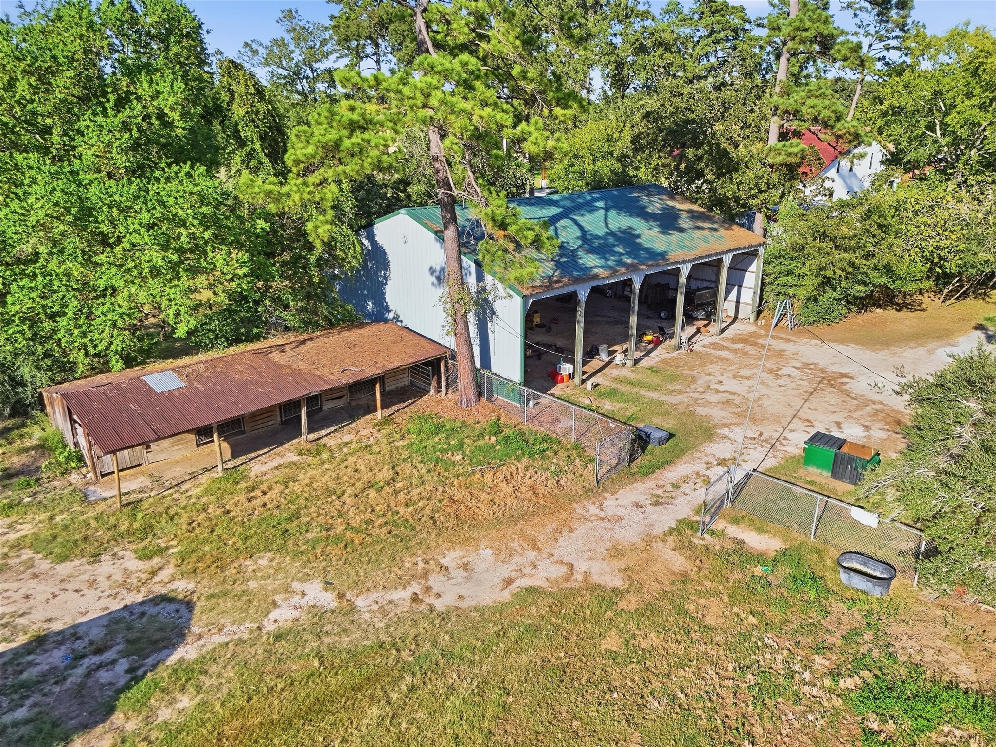 12625 Huffmeister Road Cypress, TX 77429 - Photo 35 of 50 A bird's-eye view reveals even more of the possibilities at Cy-Creek Ranch! The spacious covered equipment barn offers ample room for ranch equipment, tractors, and storage, while the adjacent animal stalls provide additional flexibility. With a little TLC and a creative vision, the existing structure could be transformed for a variety of agricultural, equestrian, or hobby farm uses. A wonderful opportunity to make this part of the ranch your own!