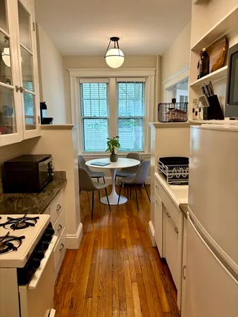 a kitchen with stainless steel appliances a stove a sink dishwasher and a dining table with wooden floor