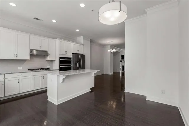 a kitchen with stainless steel appliances granite countertop a refrigerator a sink dishwasher a stove and white cabinets with wooden floor