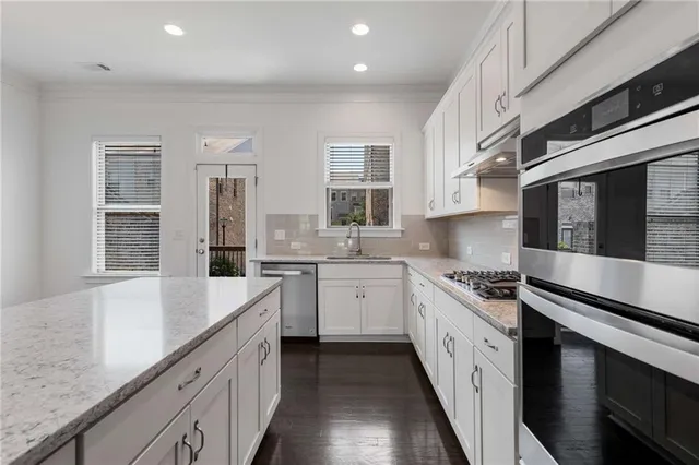 a kitchen with stainless steel appliances granite countertop a sink stove and cabinets