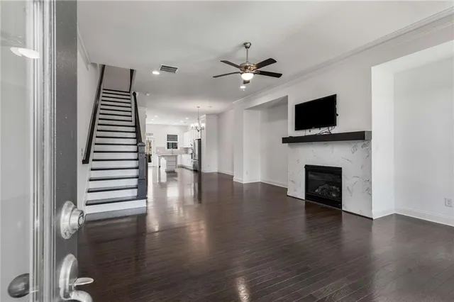 a view of a livingroom with a flat screen tv wooden floor and a ceiling fan