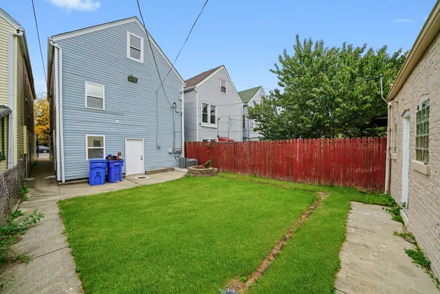 a backyard of a house with wooden fence and large trees