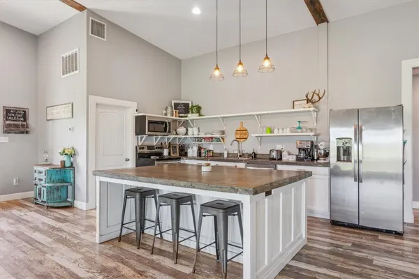 a kitchen with stainless steel appliances granite countertop a kitchen island and chairs in it