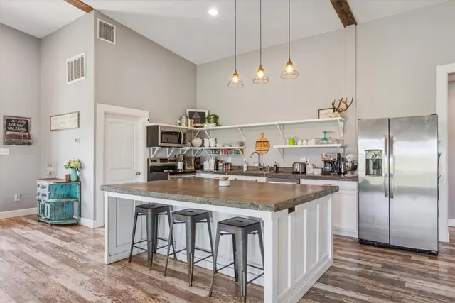 a kitchen with stainless steel appliances granite countertop a kitchen island and chairs in it