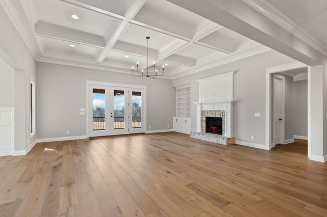 a view of an empty room with wooden floor fireplace and a window