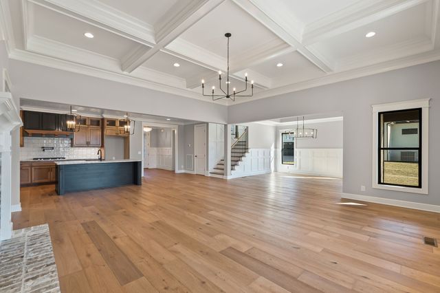 a view of a kitchen with stainless steel appliances granite countertop a oven and a large window with wooden floor