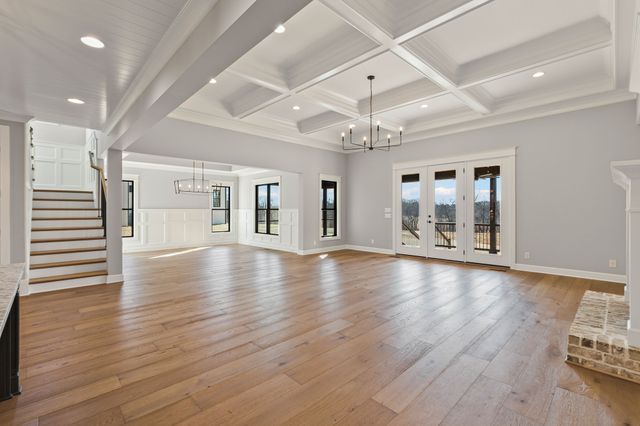 an empty room with wooden floor and large windows