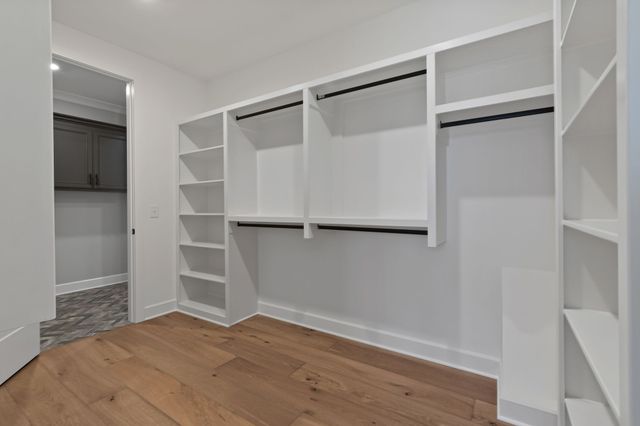 a view of an empty room with wooden floor and closet