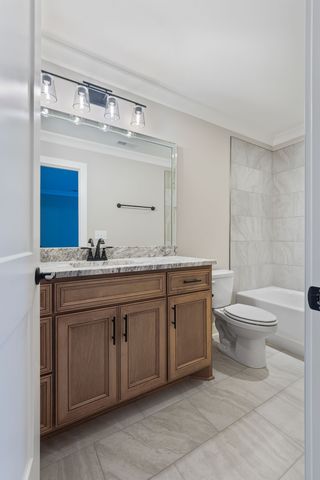 a bathroom with a granite countertop toilet a sink and a mirror