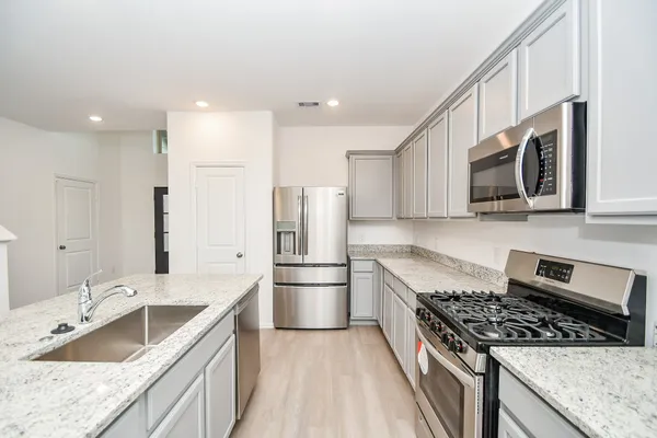 a kitchen that has a lot of cabinets a sink and wooden floor